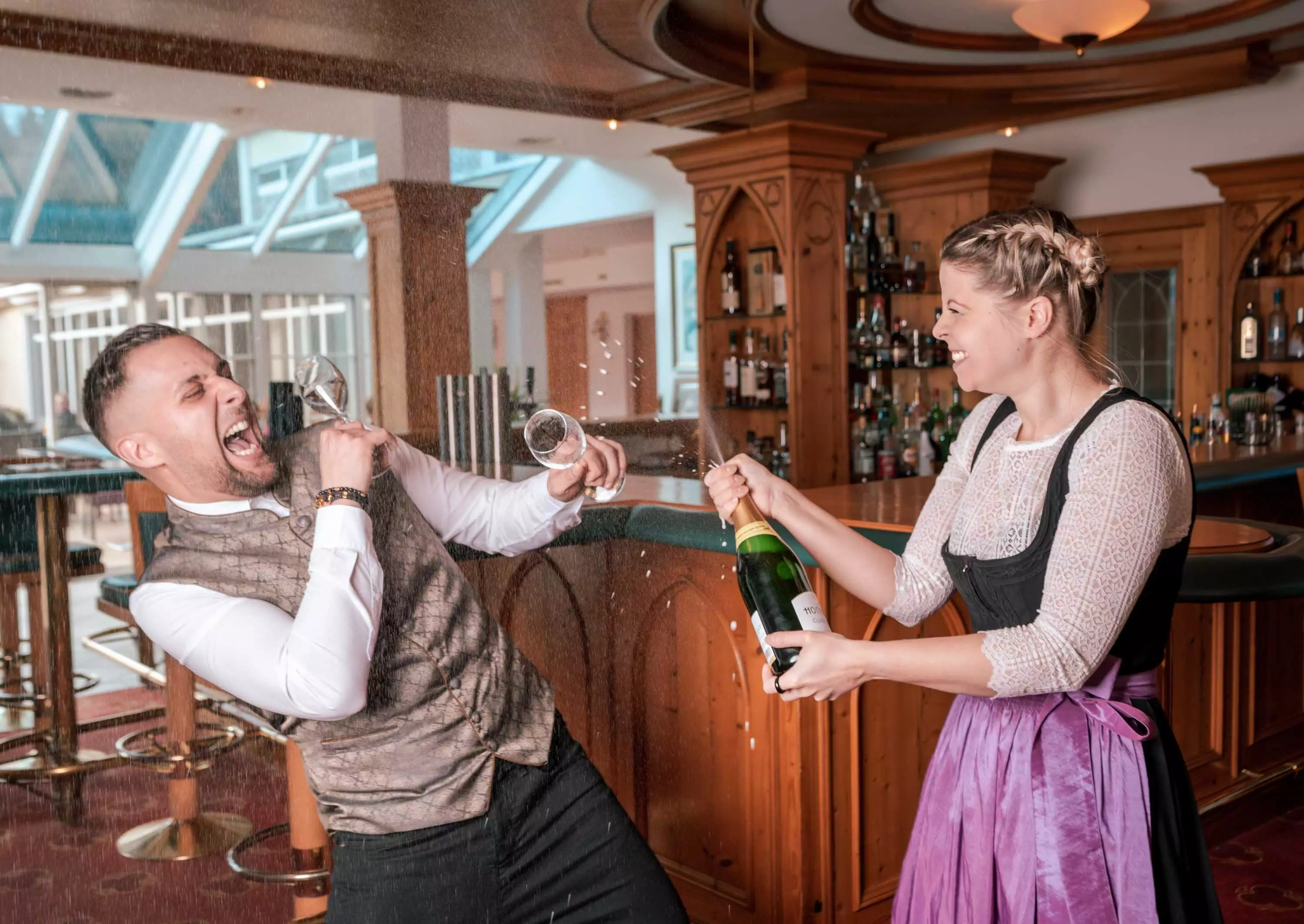 Feiernde Stimmung an der Bar mit spritzendem Champagner.